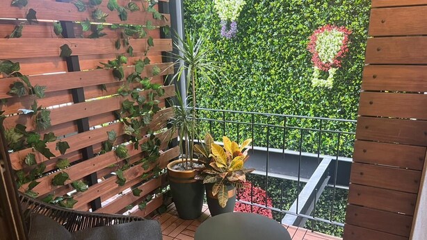 A balcony with a wooden fence, potted plants, a wicker chair, and a small table. - Acogedor MiniLoft 202 (Ciudad de México)