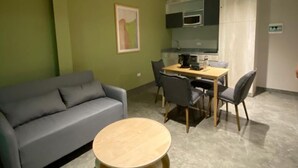A living room with a grey sofa, a round wooden coffee table, and a dining area with a table and chairs. - Acogedor MiniLoft 202 (Ciudad de México)