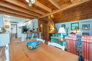 A wooden interior with a dining table, chairs, a sofa, and a kitchen area.