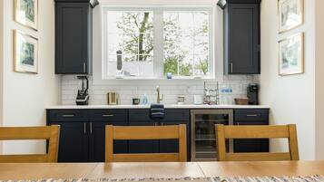 A kitchen with dark cabinets, a window, a sink, and a dining table with chairs.