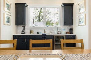 Una cocina con armarios oscuros, una ventana, un lavamanos y una mesa de comedor con sillas.