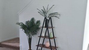 Eine Treppe mit einer weißen Wand, einer Pflanze und einem schwarzen Regal.