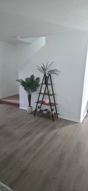 A staircase with a white wall, a plant, and a black shelf unit. - Charming 4-bedroom house with AC in lively Houston.  World Cup Central. (Houston)