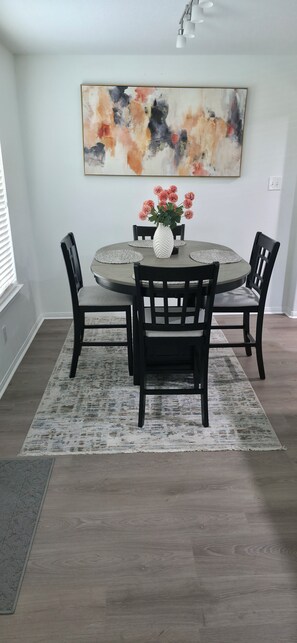A dining area with a round table, four chairs, a vase with flowers, and a large abstract painting on the wall. - Charming 4-bedroom house with AC in lively Houston.  World Cup Central. (Houston)