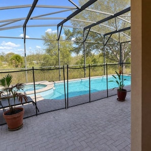 Ein überdachter Außenbereich mit Pool, Kübelpflanzen und Blick auf Bäume.