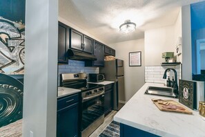 A kitchen with dark cabinets, a stainless steel oven, a microwave, and a refrigerator. - Dakmel Terrace Retreat (Southgate)