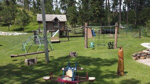 A playground with swings, a slide, and a climbing structure. - Moose Haven Cabin, full kitchen, cover carport, Restmore Inn, Hill City (Hill City)