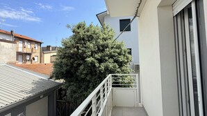 A balcony with a metal railing, a white awning, and a large tree in the background. - Modern Sea Apartment (Punta Marina)