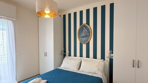 A bedroom with a bed, a hanging light fixture, a wall-mounted picture, and a wardrobe. - Modern Sea Apartment (Punta Marina)