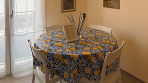 A dining area with a round table, chairs, a hanging light fixture, and two framed artworks on the wall. - Modern Sea Apartment (Punta Marina)