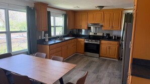 Una cocina con armarios de madera, una estufa de acero inoxidable y una mesa de comedor con sillas.