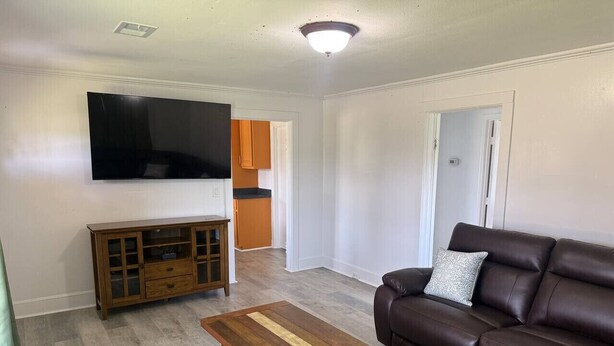 Una sala de estar con un sofá de cuero marrón, una mesa de centro de madera y un televisor montado en la pared.