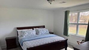 Un dormitorio con una cama de madera, una mesita de noche, un aparador y una ventana con cortinas.