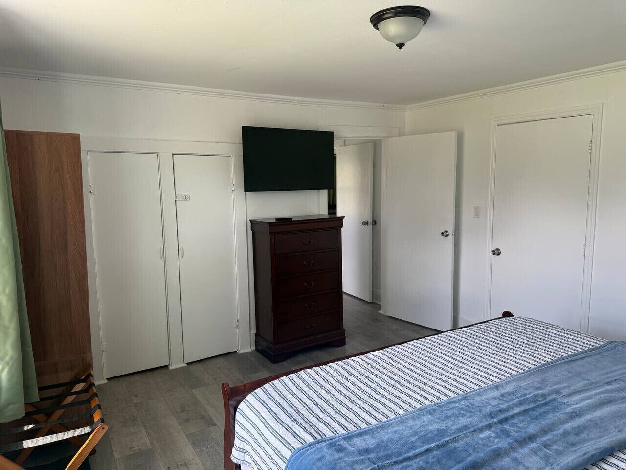 Un dormitorio con cama, cómoda y dos puertas.