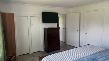 Un dormitorio con cama, cómoda y dos puertas.