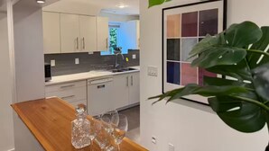 Eine moderne Küche mit weißen Schränken, einer Holzausziehtafel und einem Blumentopf.