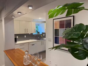 Una cocina moderna con armarios blancos, encimera de madera y una planta en maceta.