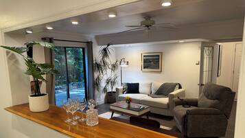 A modern living room with a wooden coffee table, a sofa, a recliner, and a potted plant.