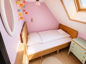 A single bed with a wooden frame, a bedside table, a mirror, and a wall decoration. - Ocean View Apartment - Heart of Tórshavn (Tórshavn)