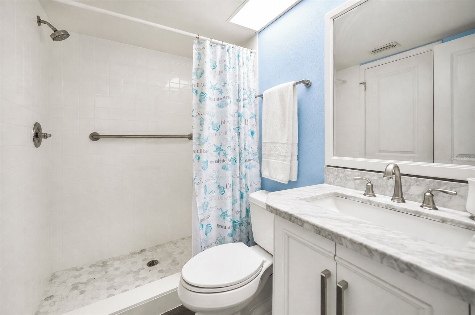 A bathroom with a shower, toilet, and sink with a marble countertop.