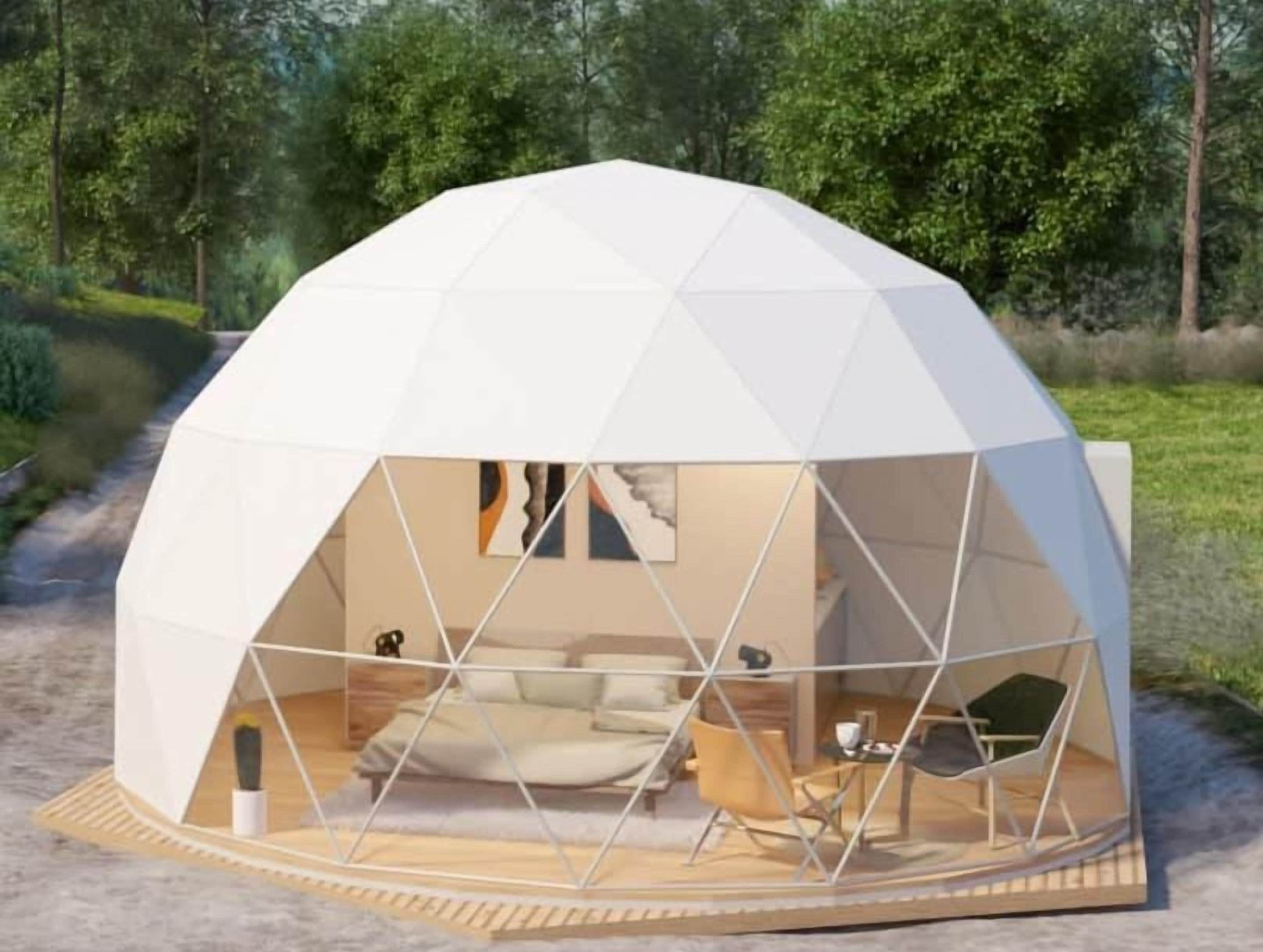 Estructura en forma de geodésica con un interior visible que incluye una cama, una zona de estar y una pequeña mesa.