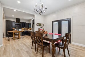 A dining area with a wooden table and chairs, a chandelier, and a kitchen in the background. - Dallas- Central Location, Spacious Backyard- Pets Welcomed (Dallas)