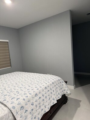 A bedroom with a bed, a window with blinds, and a dark wall. - Spacious Florida Keys Escape. Family Friendly (Florida City)