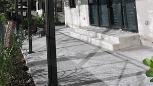 Un bâtiment moderne doté d’un patio couvert, de grandes fenêtres et d’un chemin en béton.