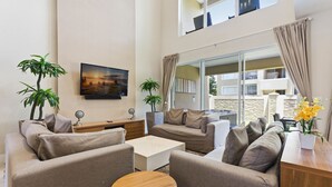 A modern living room with a sofa set, a coffee table, and two potted plants. - Upscale 3BR Suites, Patio With BBQ & Jacuzzi (Kissimmee)