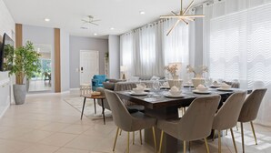 Een moderne eetruimte met een grote tafel voor zes personen, omringd door grijze stoelen met gouden poten.
