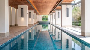 Una lunga piscina al coperto con soffitto in legno e pareti bianche.