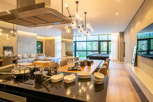 A modern kitchen with a central island, dining area, and a pool table. - Studio Simpático - Moema (São Paulo)
