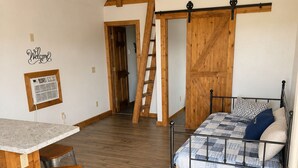 A loft-style bedroom with a bed, a desk, and a ladder.