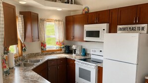 A compact kitchen with wooden cabinets, a microwave, an oven, and a refrigerator.