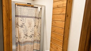 A bathroom with a toilet, a shower curtain, and wooden paneling.