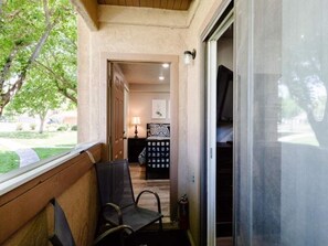 Ein Balkon mit einem Stuhl, einer zur Kammer führenden Tür und Blick auf einen Garten.
