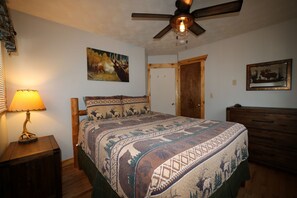 A bedroom with a bed, a ceiling fan, a lamp, and a door. - Elk Ridge Vacation Home, 3 bedrooms, 1 bath, downtown Hill City (Hill City)