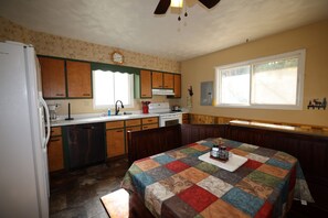 A compact kitchen with wooden cabinets, a refrigerator, a sink, and a stove. - Elk Ridge Vacation Home, 3 bedrooms, 1 bath, downtown Hill City (Hill City)
