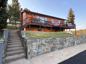 A two-story building with a stone staircase leading to a porch. - Elk Ridge Vacation Home, 3 bedrooms, 1 bath, downtown Hill City (Hill City)