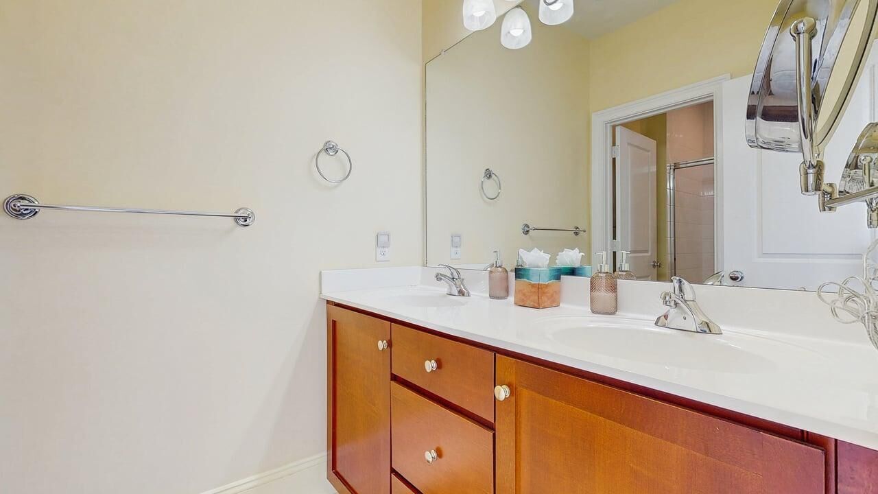 A bathroom with a white sink, wooden vanity, a towel rack, and a mirror.