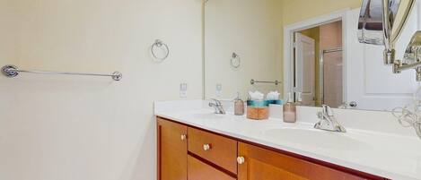 A bathroom with a white sink, wooden vanity, a towel rack, and a mirror.
