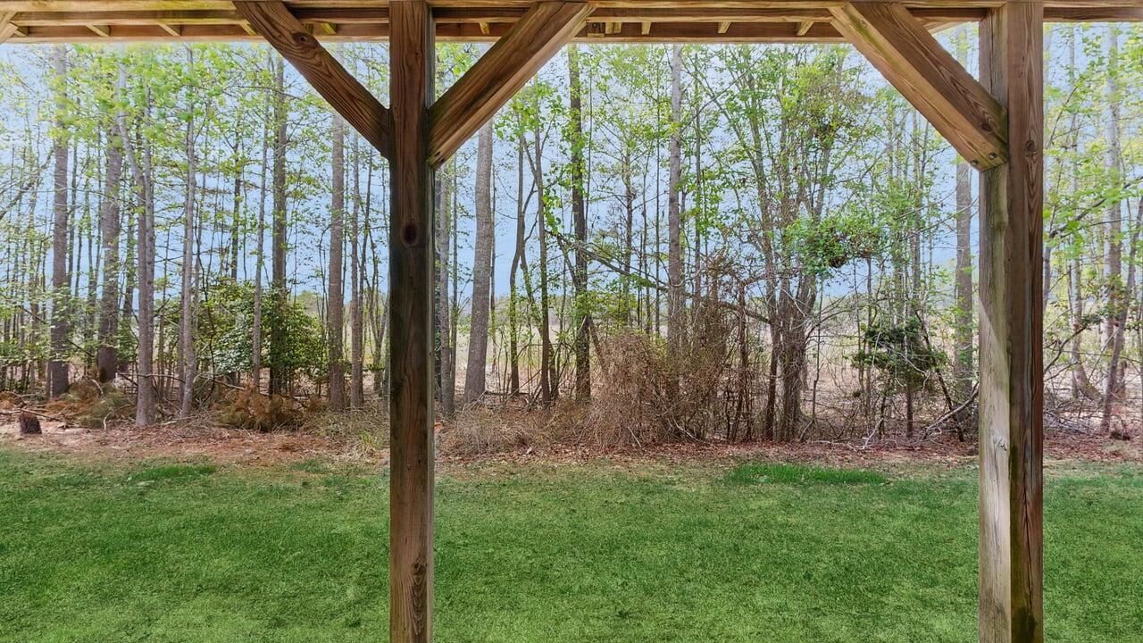 A wooden pergola structure with a view of a forested area.