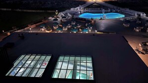Uma área de piscina no terraço com vista para o oceano, mobiliário de jardim e uma estrutura de ponte coberta.