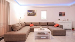 Ein modernes Wohnzimmer mit einem Ecksofa, einem Couchtisch und einer weißen Kommode.