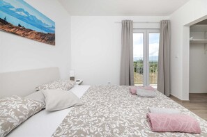 A bedroom with a bed, pillows, a nightstand, a painting, and a balcony with curtains. - Villa Vera-swimming pool, 12 PAX (Donji Kašić)