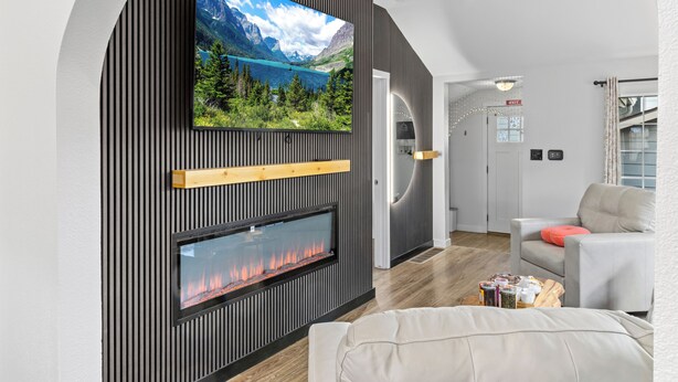 Ein modernes Wohnzimmer mit an der Wand montiertem Fernseher, Kamin und gemütlicher Sitzecke.