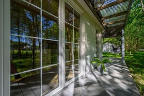 A covered outdoor area with large glass windows, a hammock, and potted plants. - Comfortable Holiday Home no. 4B With a Fireplace (Darlowo)