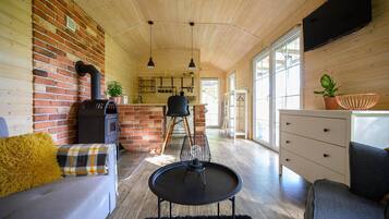 Un interior acogedor con pared de ladrillo, techo de madera, un sofá, una mesa de comedor y una zona de cocina.