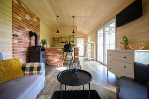 A cozy interior with a brick wall, wooden ceiling, a sofa, a dining table, and a kitchen area. - Comfortable Holiday Home no. 4B With a Fireplace (Darlowo)