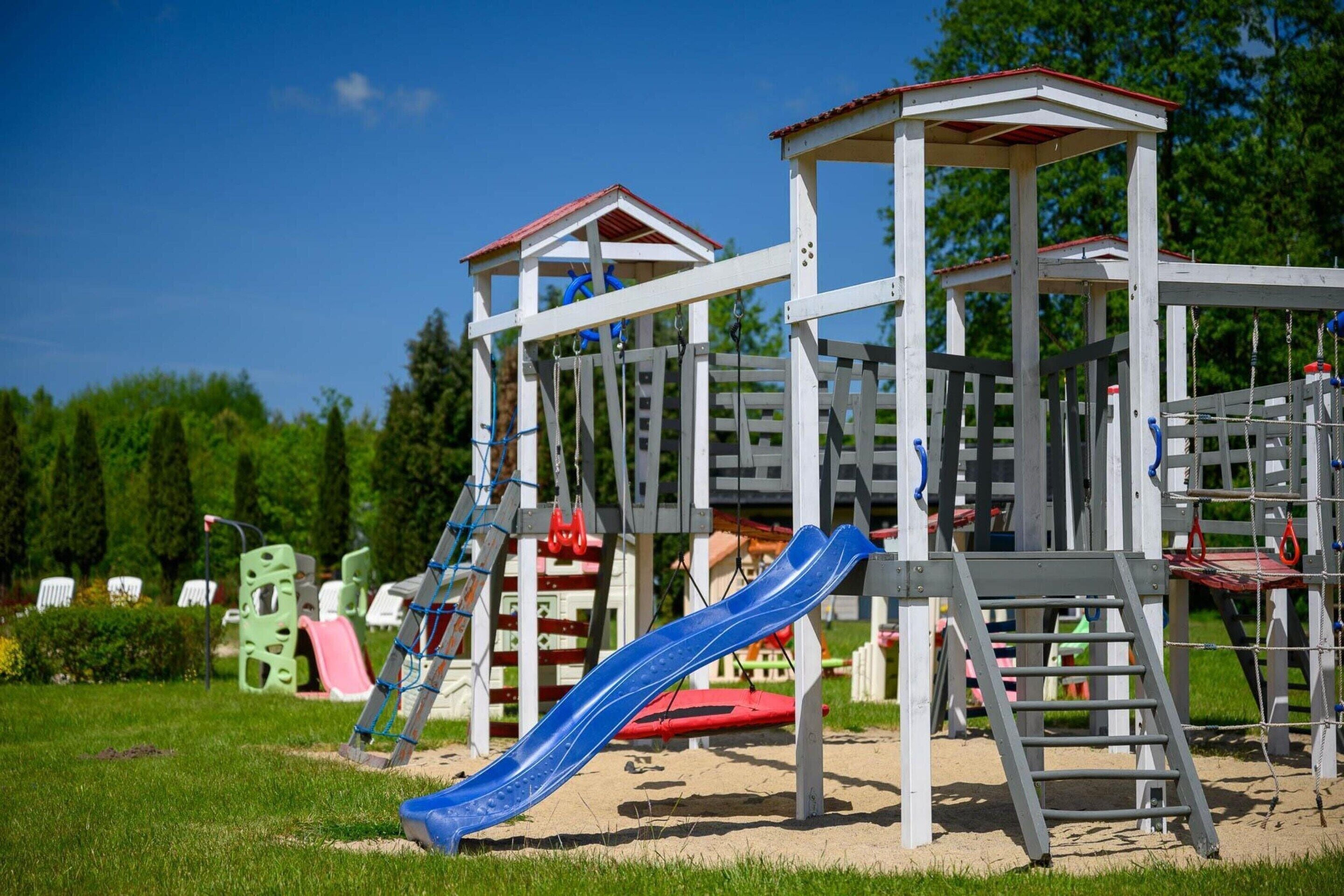 Un parque infantil con tobogán, estructuras para escalar y una casita cubierta.